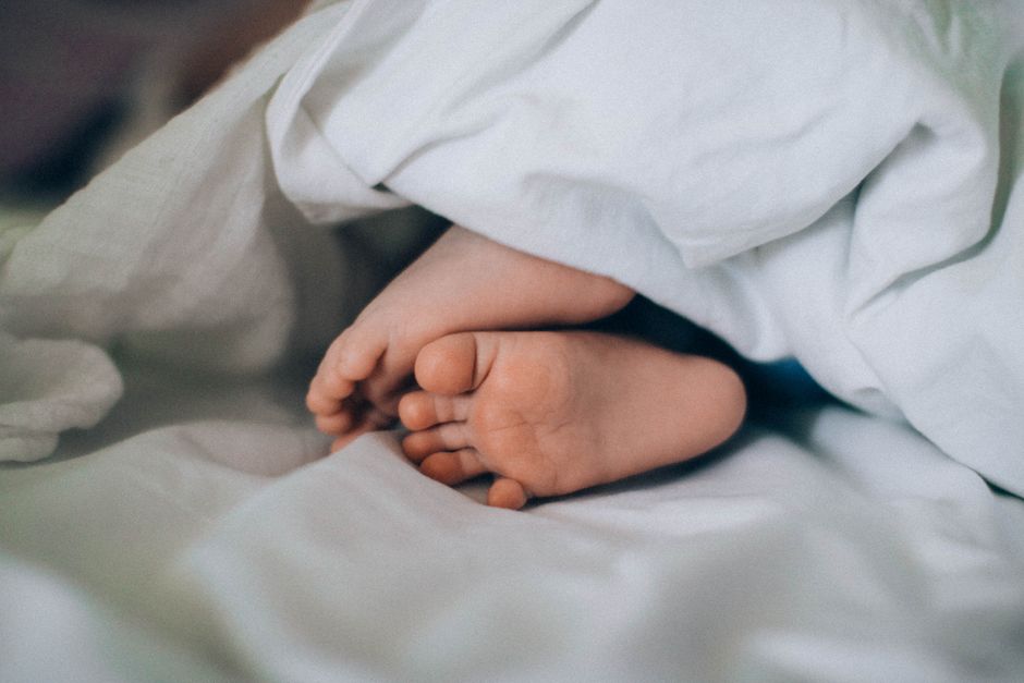 Close-up of tiny baby feet under a blanket, creating a cozy, cute vibe.