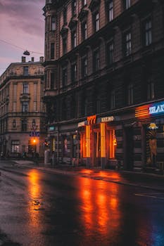 Exterior of empty city street with facades of old buildings and illuminated shop windows in evening
