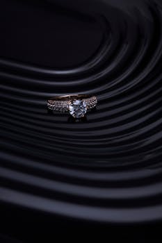 黑色波浪背景衬托下的钻石戒指特写，营造出奢华优雅的氛围