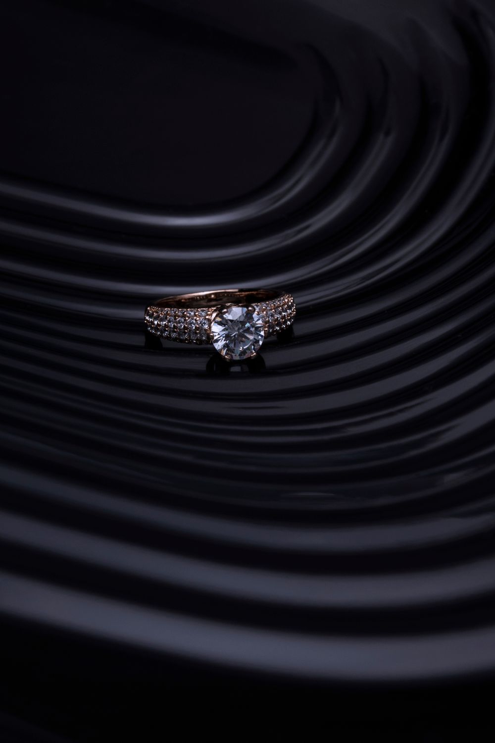 Solitaire ring against a dark sculpted background