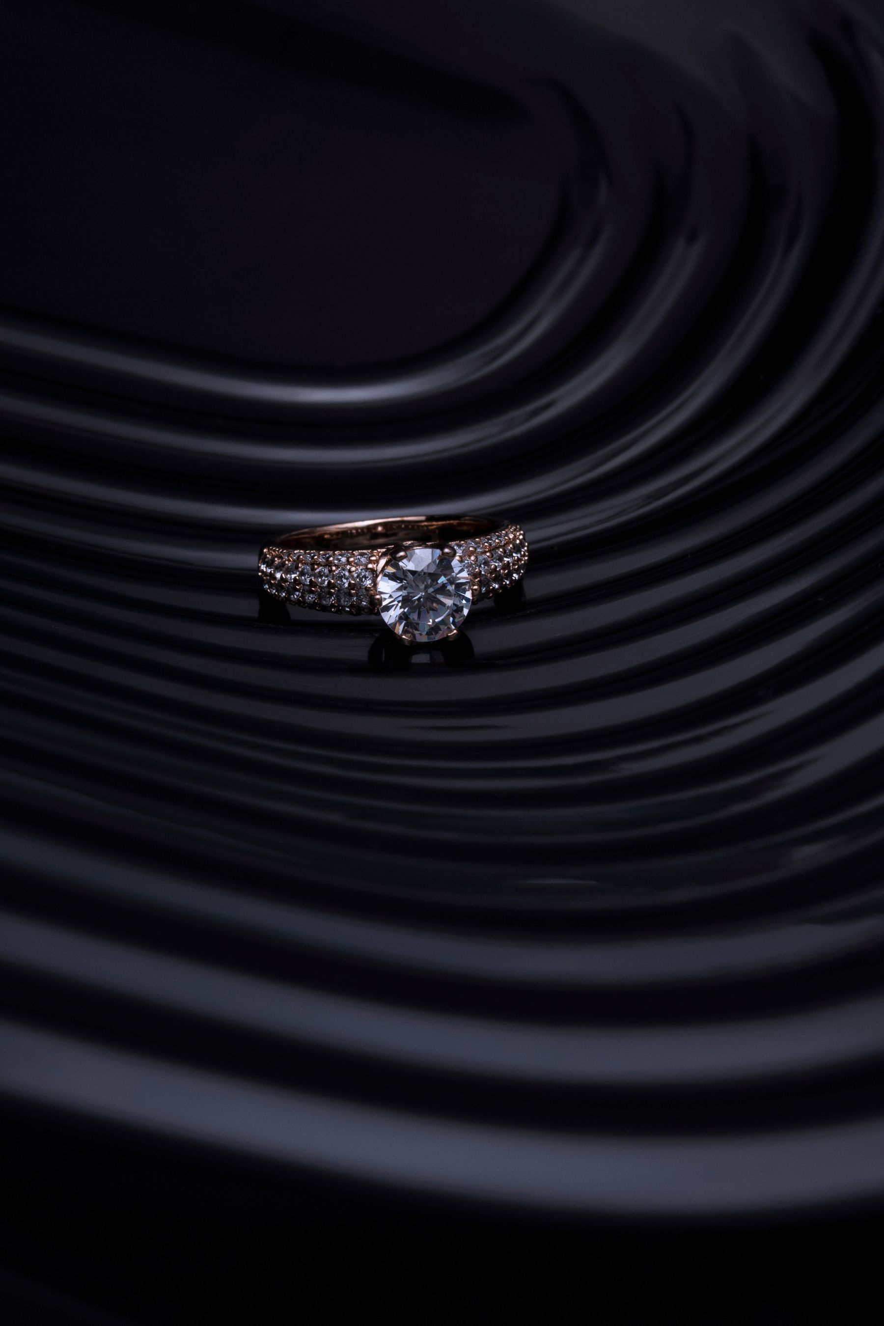 A solitaire ring against a sculpted dark ground