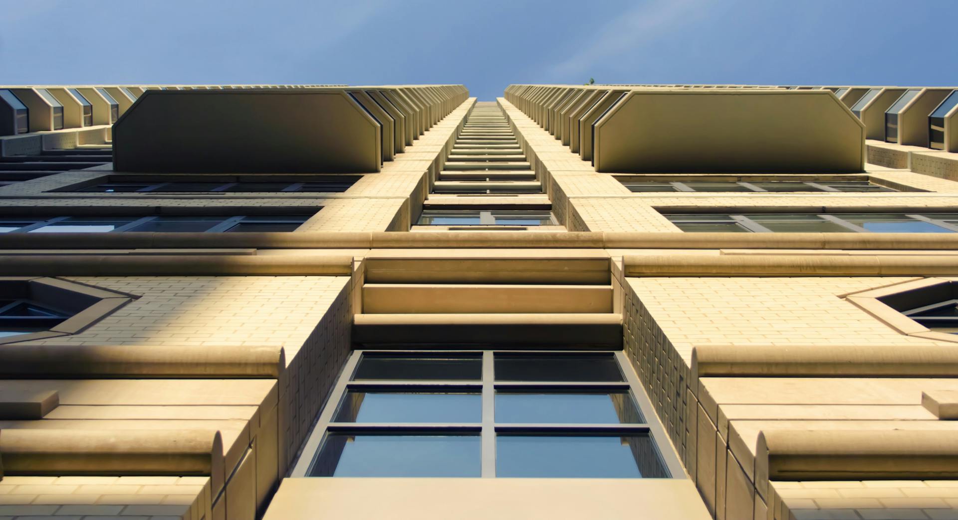 Low-angle view of a modern skyscraper with glass windows against a clear sky.