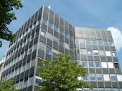 低角度视角下的现代办公楼，映衬着清澈的蓝天，绿树环绕