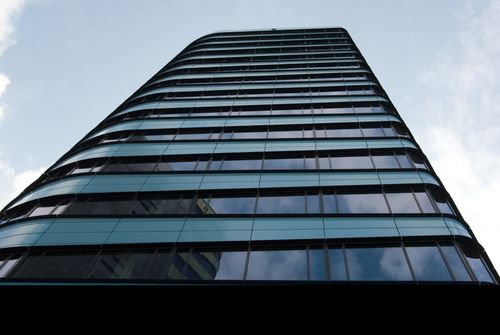 Free Low angle view of a modern skyscraper with reflective glass windows against the sky. Stock Photo