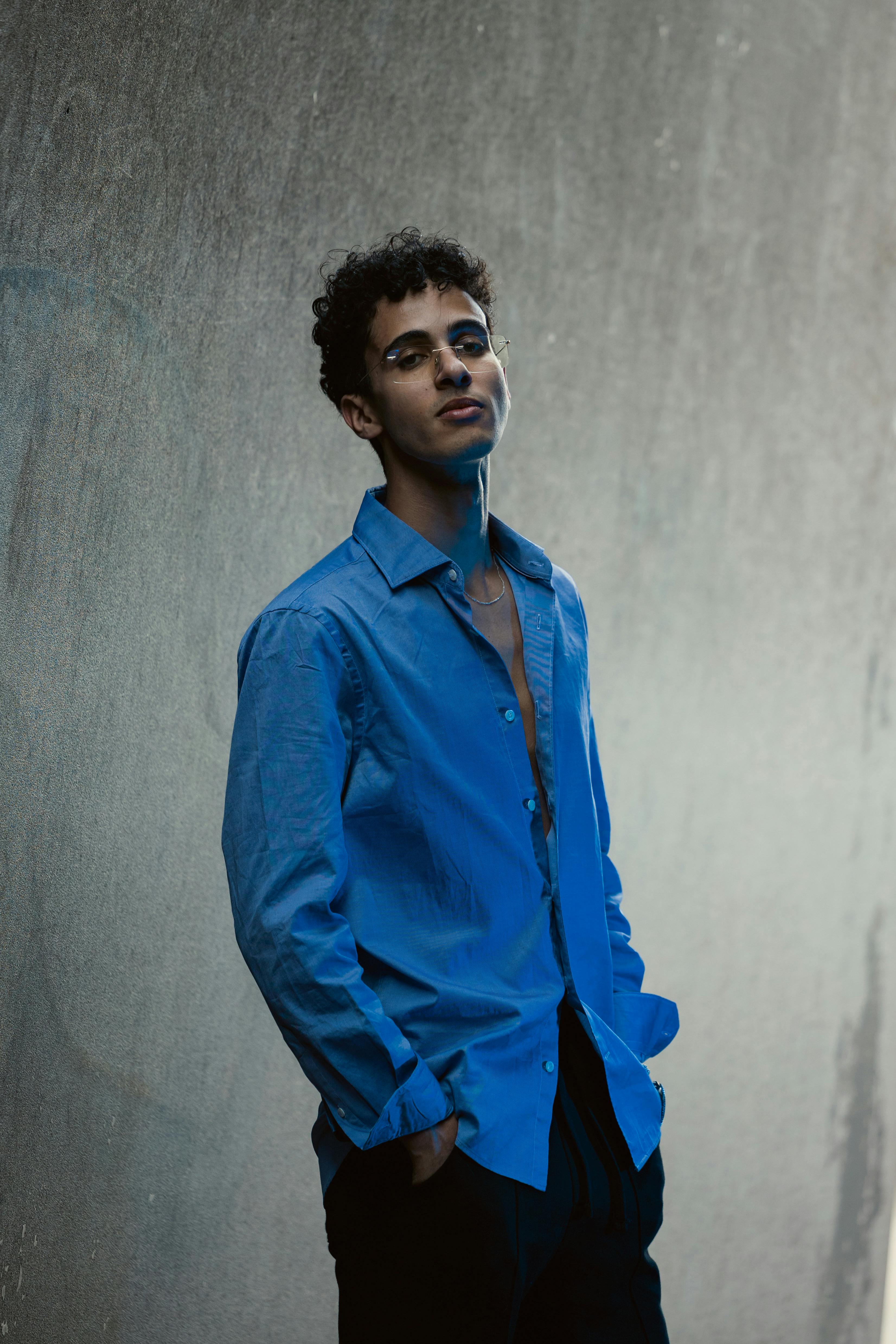 a man in a blue shirt standing against a wall