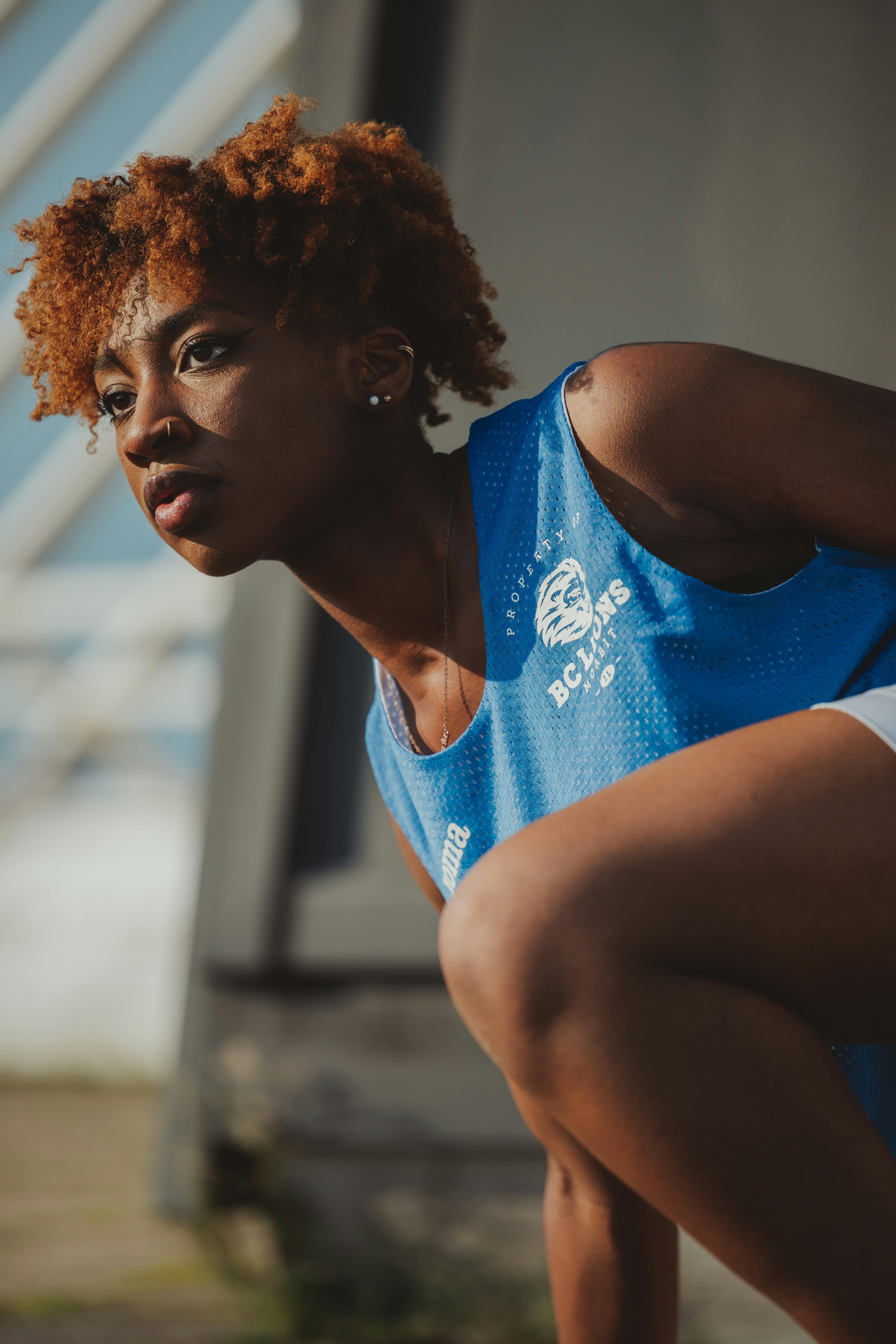 Free Portrait of a young female athlete outdoors, readying for physical activity on a sunny day. Stock Photo