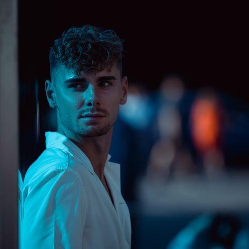 Free A young man in a white shirt under moody blue lighting, creating a cinematic feel. Stock Photo