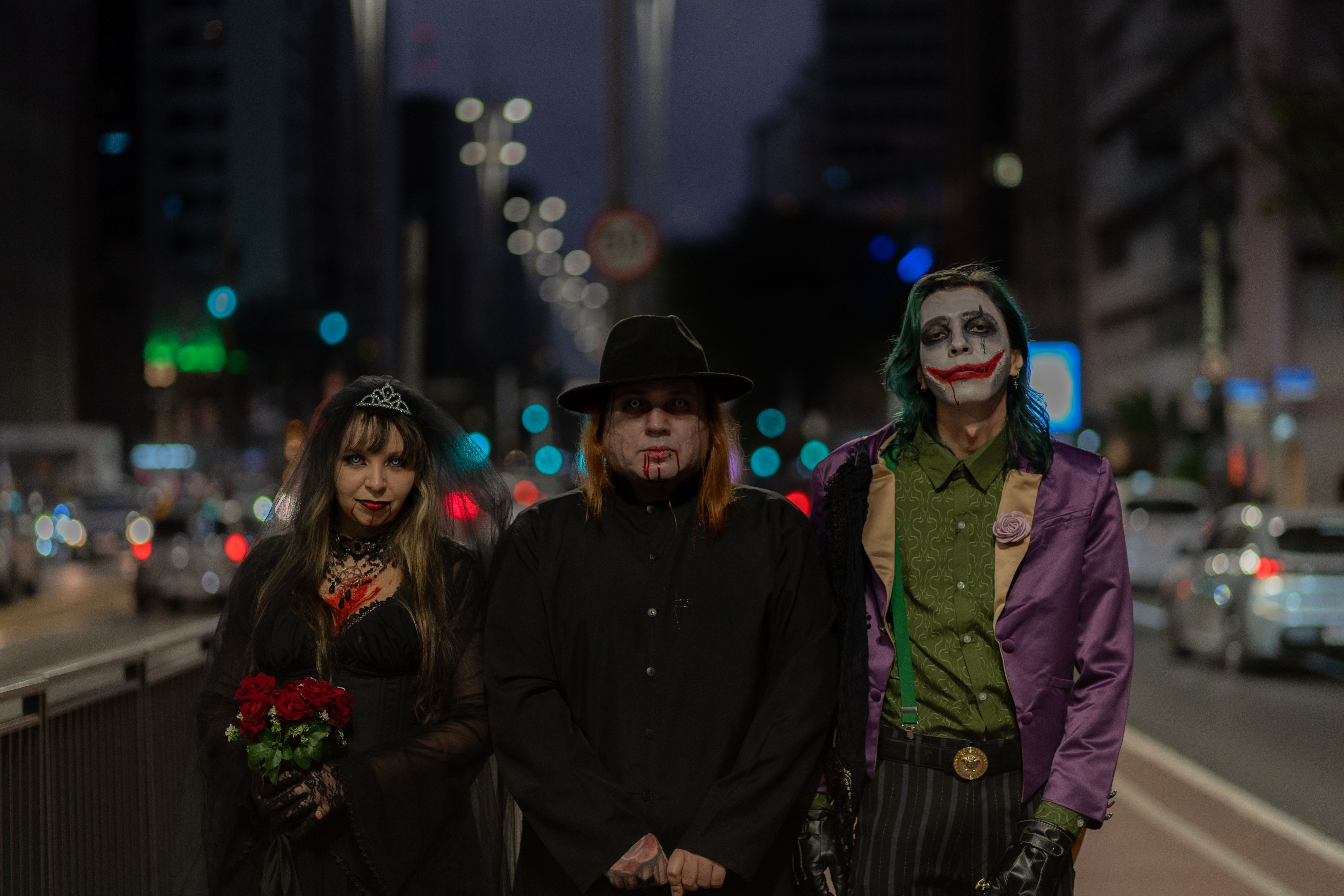 A trio in Halloween-themed cosplay walking through a bustling city street at night.