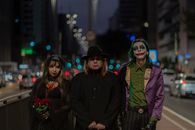 A trio in Halloween-themed cosplay walking through a bustling city street at night.