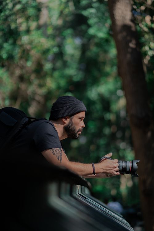 Free A focused man capturing the beauty of nature with a professional camera outdoors. Stock Photo