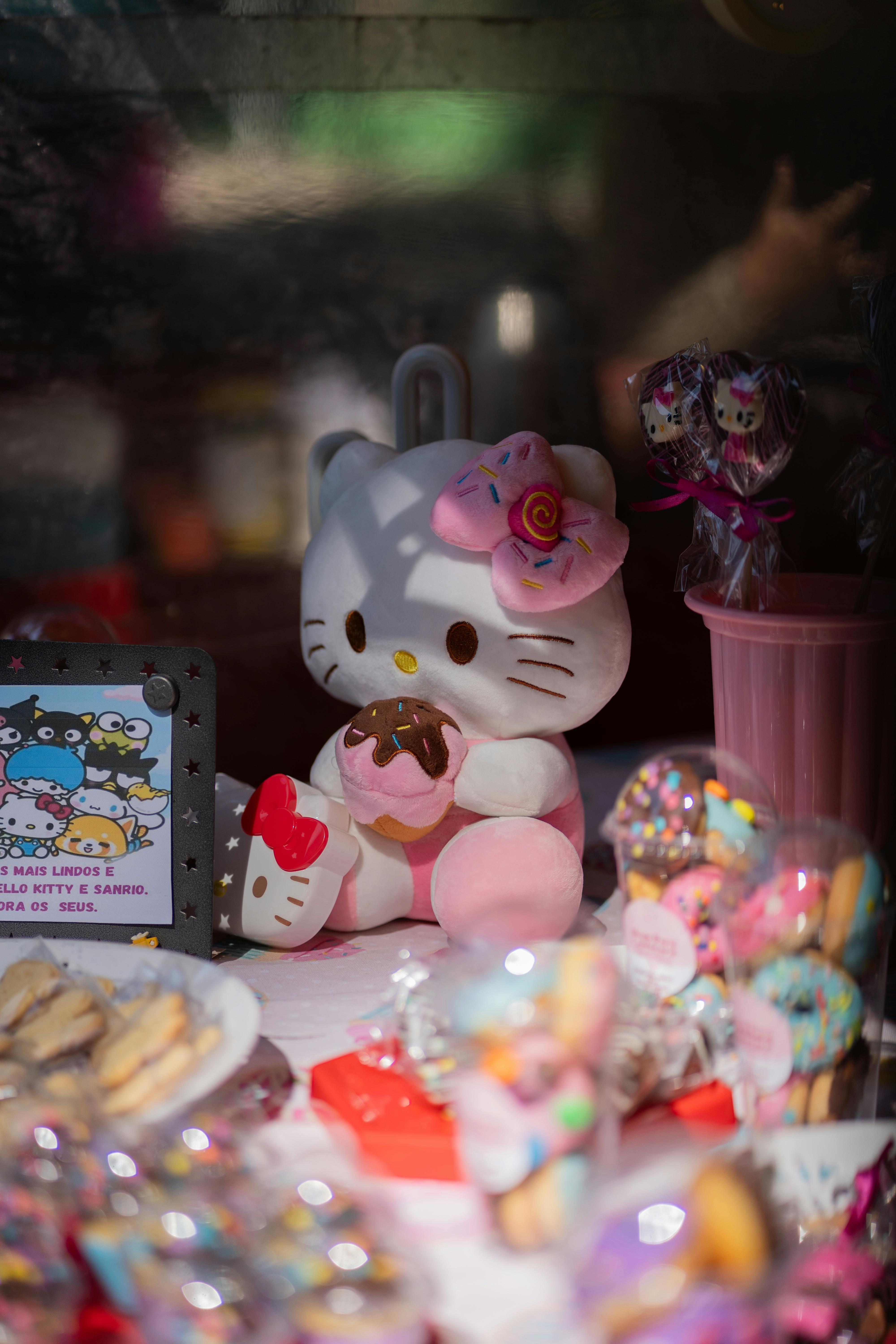 a hello kitty doll sitting on a table with a bunch of sweets