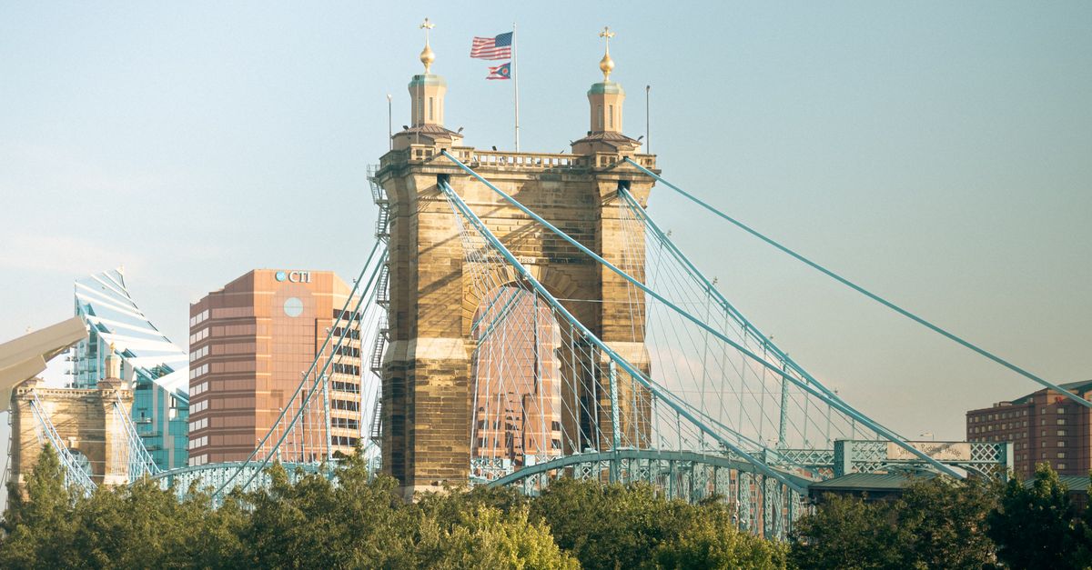 Iconic John A. Roebling Suspension Bridge spanning the Ohio River with a cityscape backdrop.