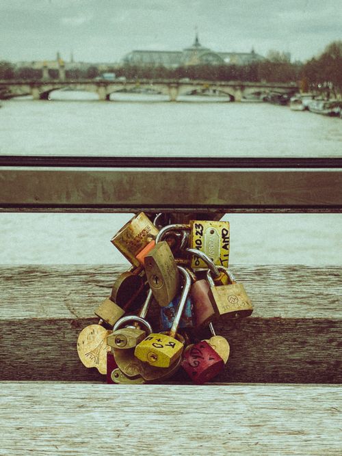 Free A collection of colorful love locks on a Paris bridge railing, with the River Seine and cityscape in the background. Stock Photo