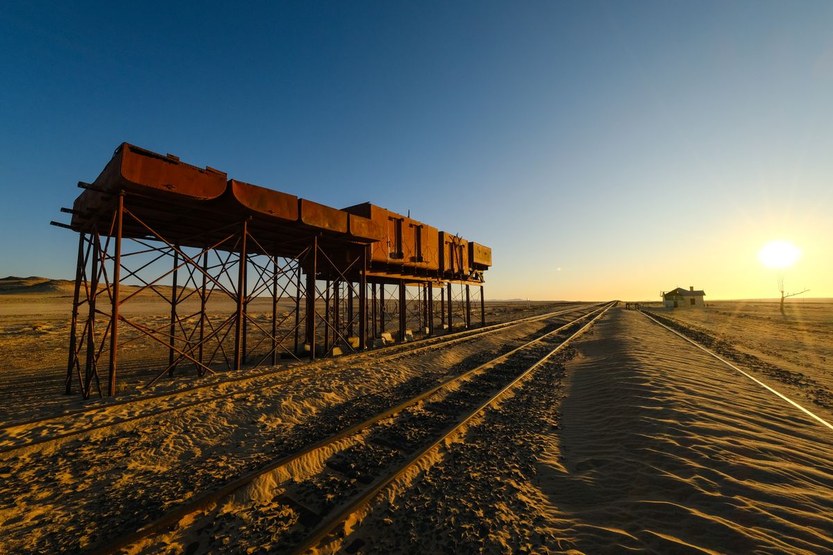 a single golden spike being driven into a desert railway by a clown