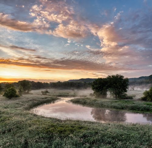 Free A tranquil sunrise landscape in Modena, WI, showcasing a reflective river and soft mist over a grassy field. Stock Photo
