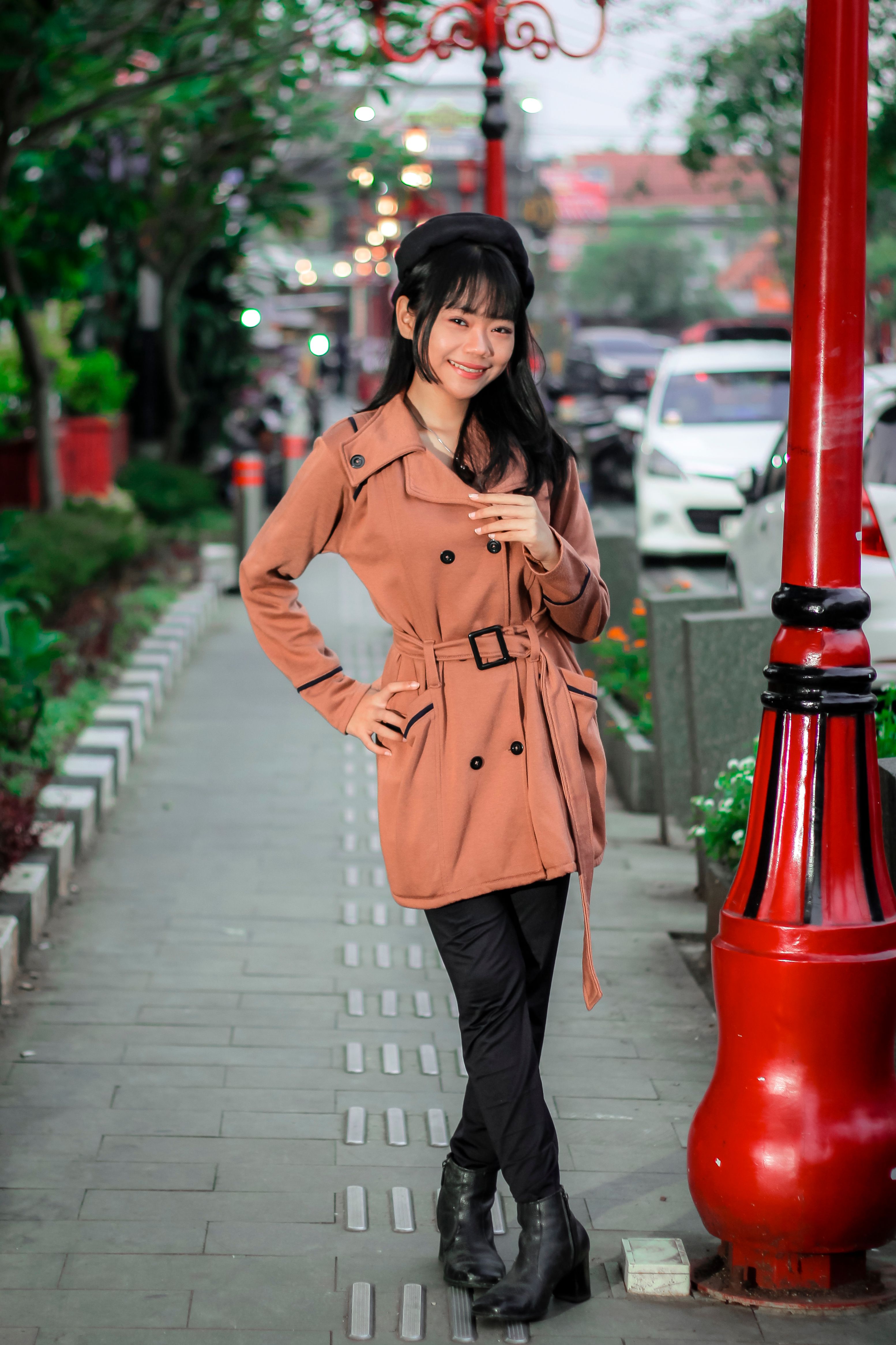 A Young Woman in a Coat Standing on a Sidewalk · Free Stock Photo