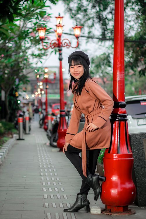 A Young Woman in a Coat Standing on a Sidewalk · Free Stock Photo