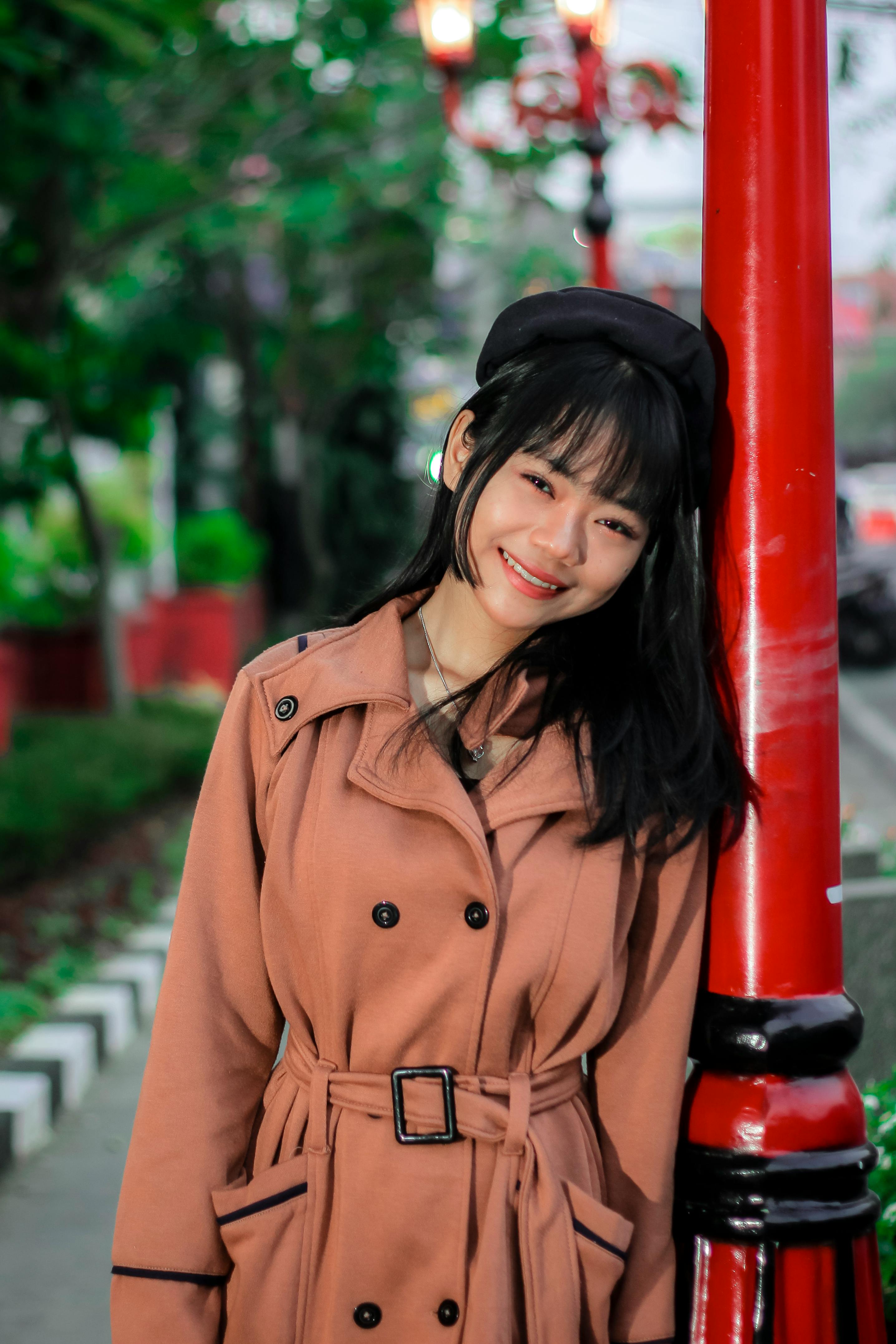 a young woman in a trench coat posing for a photo