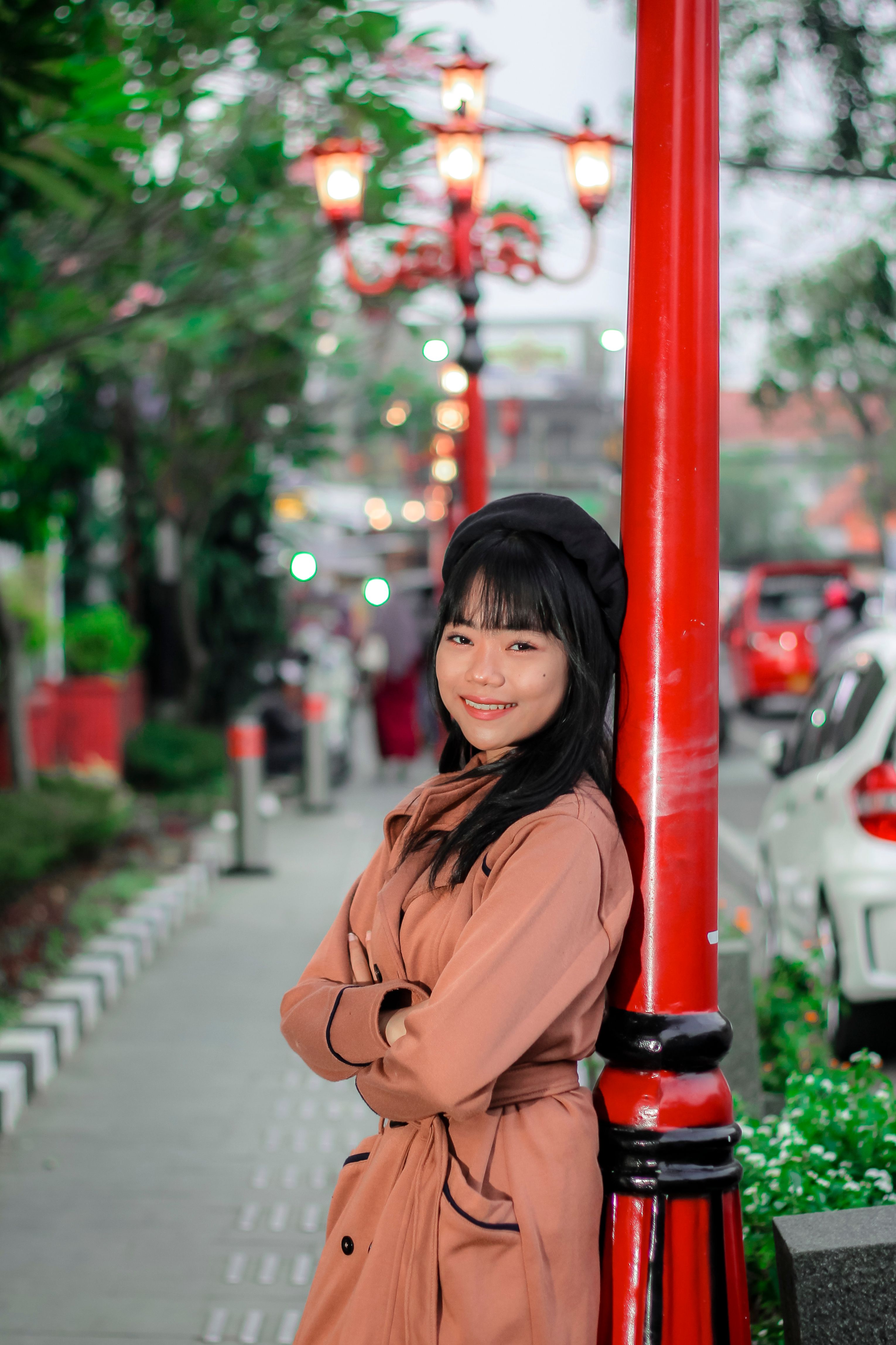 A Young Woman in a Coat Standing on a Sidewalk · Free Stock Photo