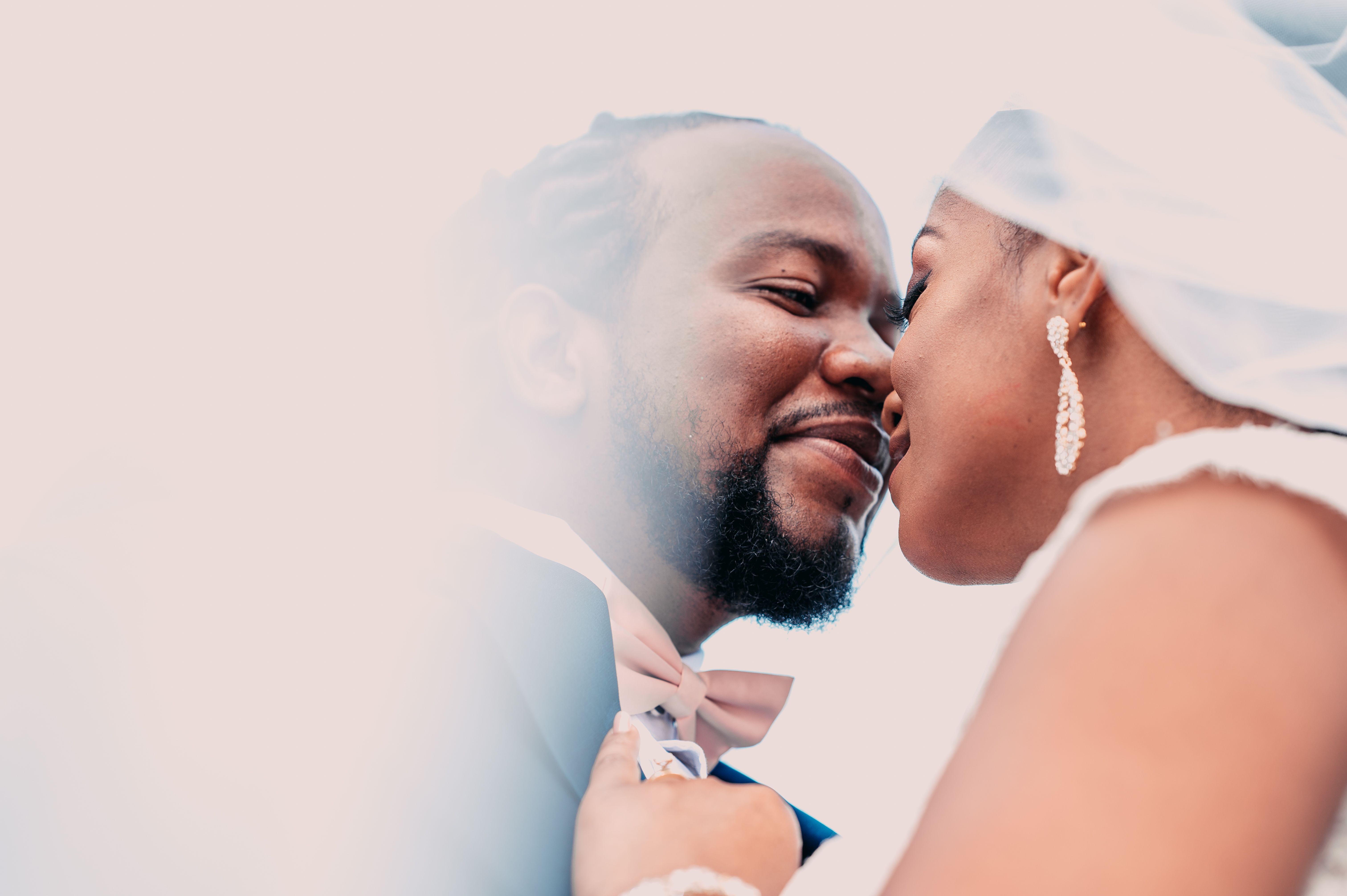 A bride and groom kiss in front of a cloud · Free Stock Photo