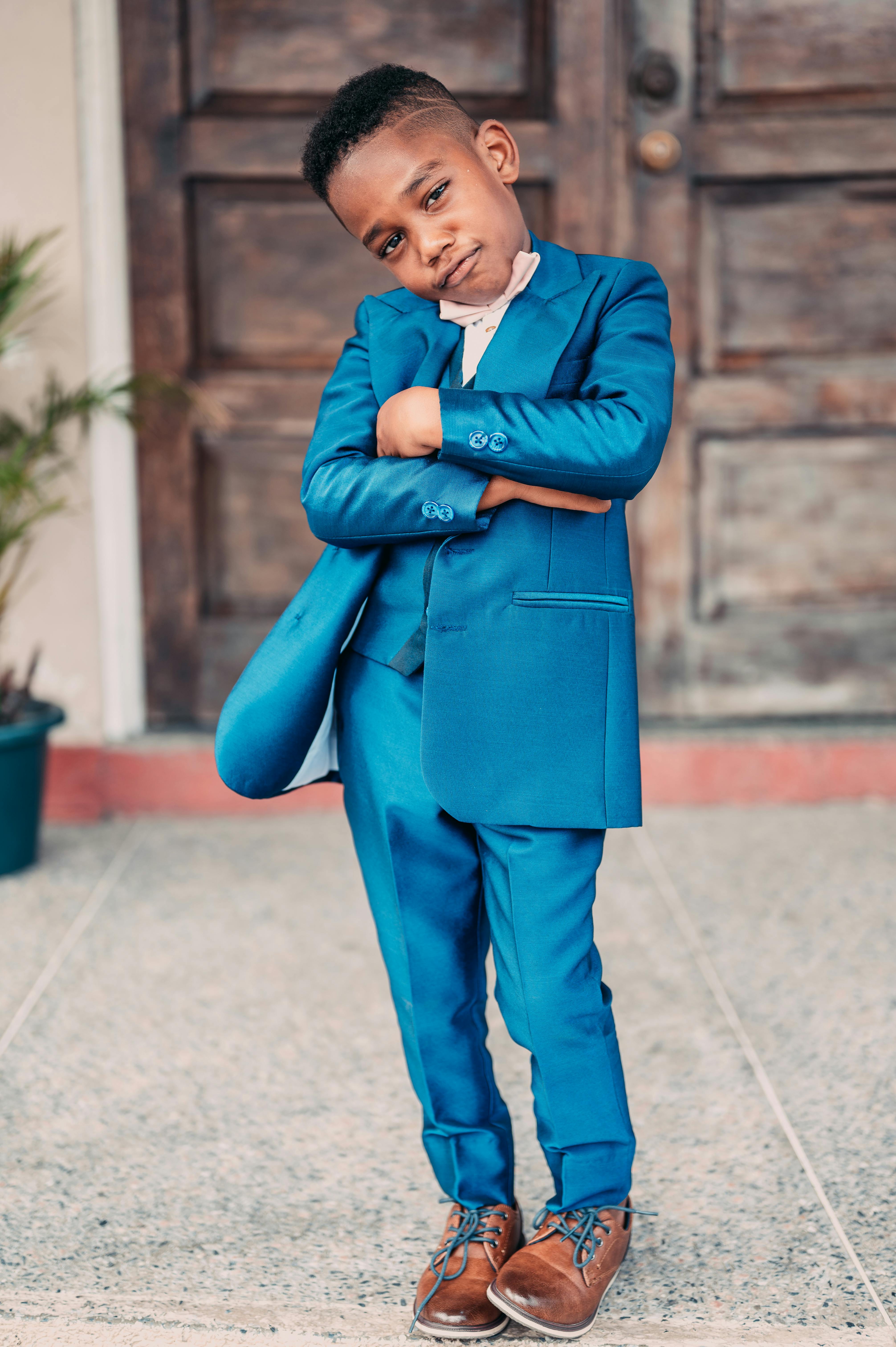 Adorable child in a blue suit striking a confident pose outdoors in Port of Spain.
