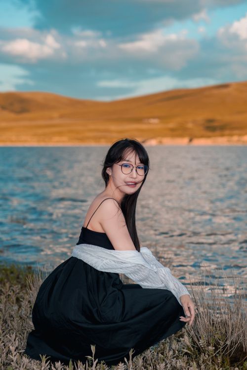 Free A woman enjoying a tranquil lakeside view during sunset, embracing the serenity of nature. Stock Photo