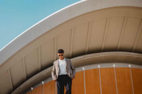 Free Man in stylish attire standing in front of Berlin's iconic architecture on a sunny day. Stock Photo