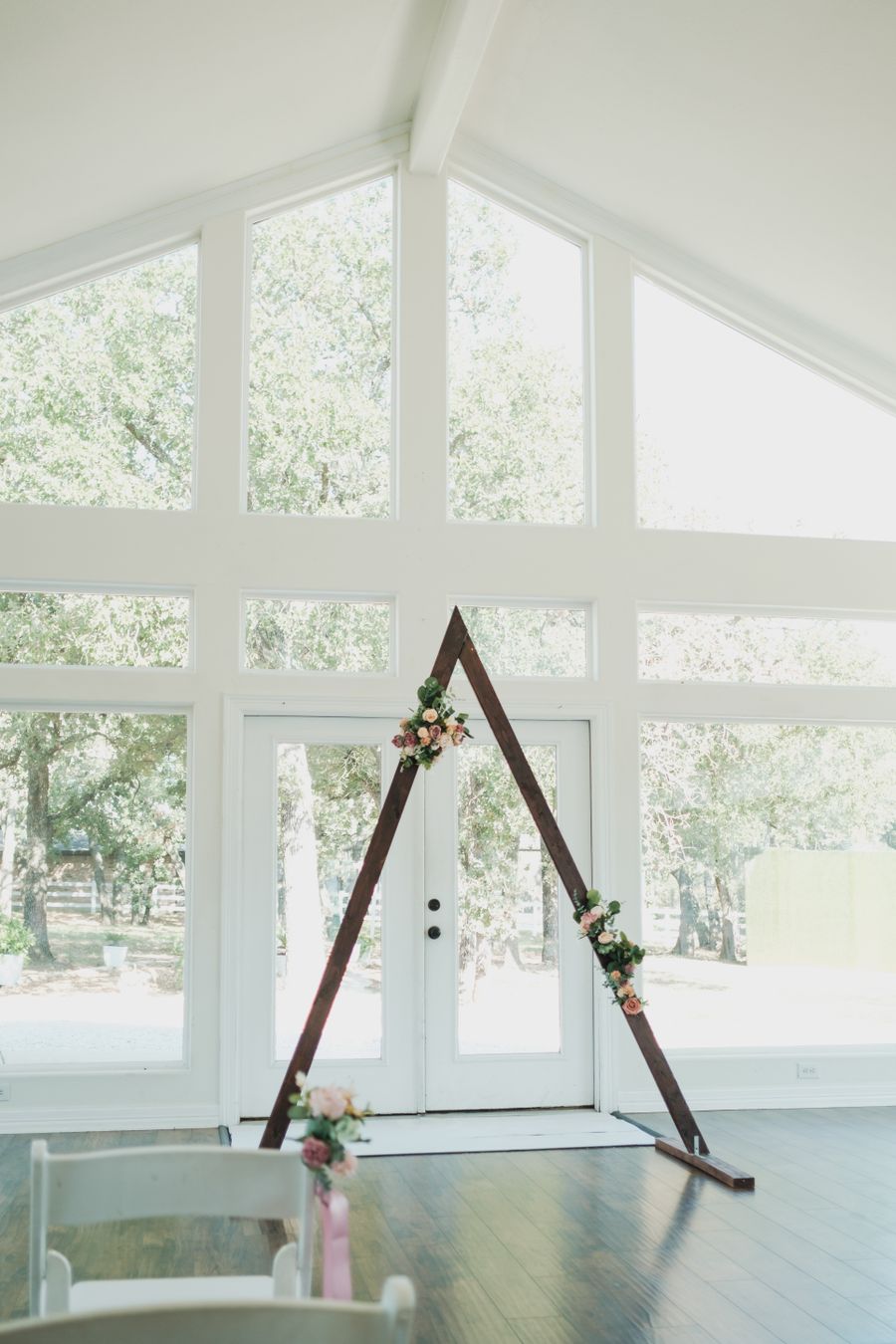 A walnut ceremony arch dressed with blush and white flowers