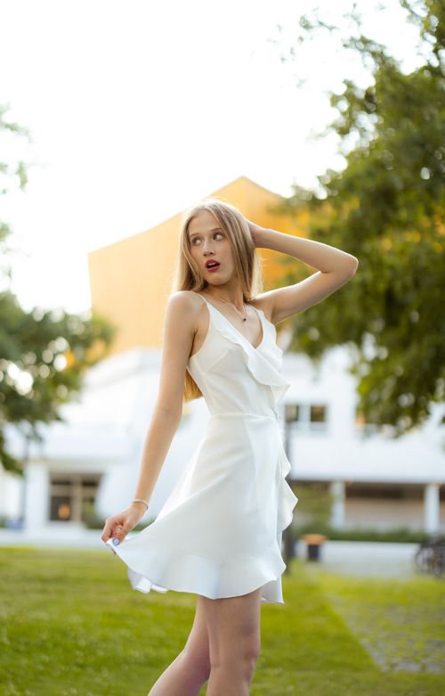 Free Woman in a white dress posing gracefully outdoors in Berlin during summer. Stock Photo
