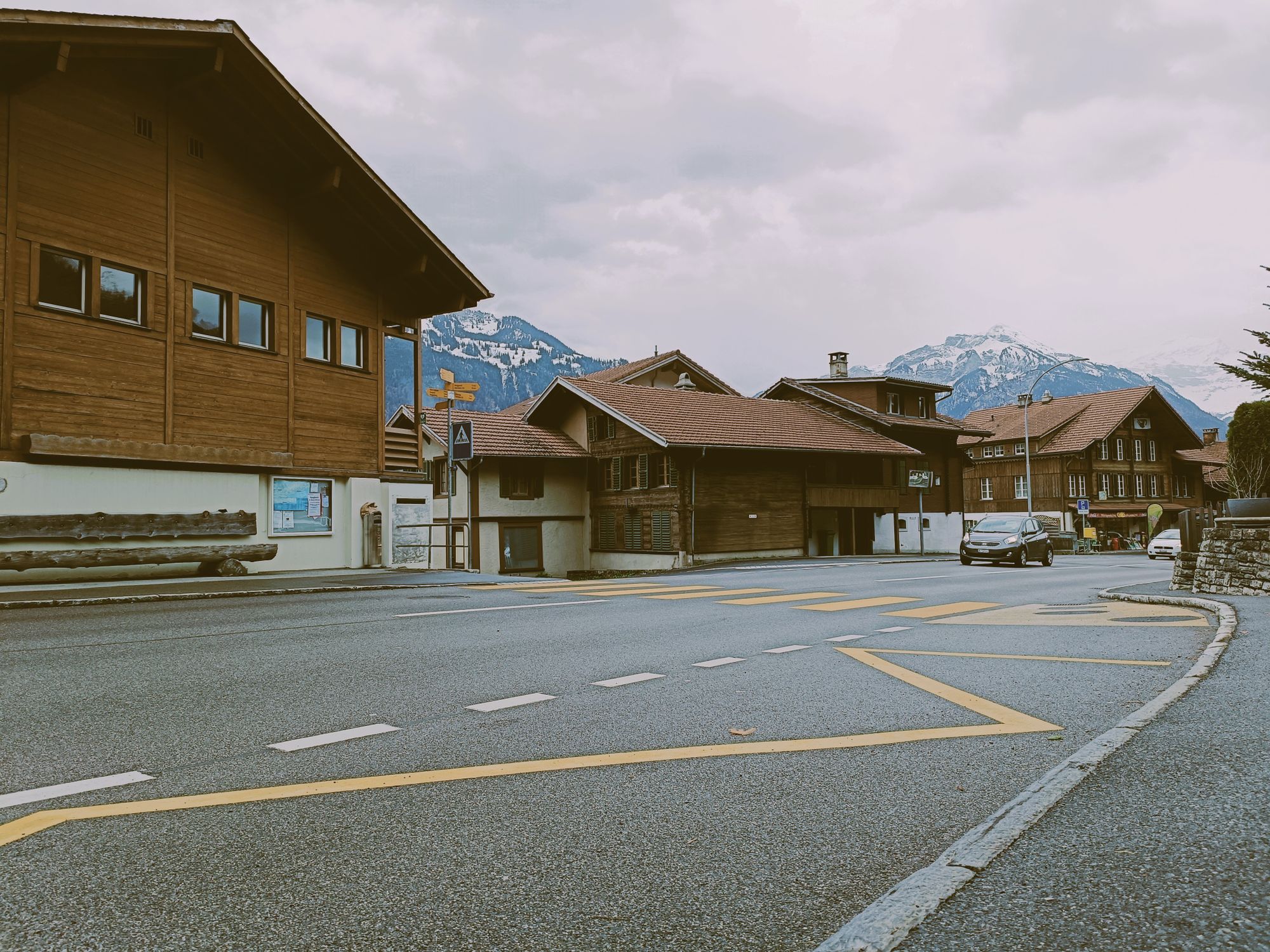 Scenic view of traditional Swiss chalets on a quiet street in Interlaken, Switzerland, near snow-capped mountains.