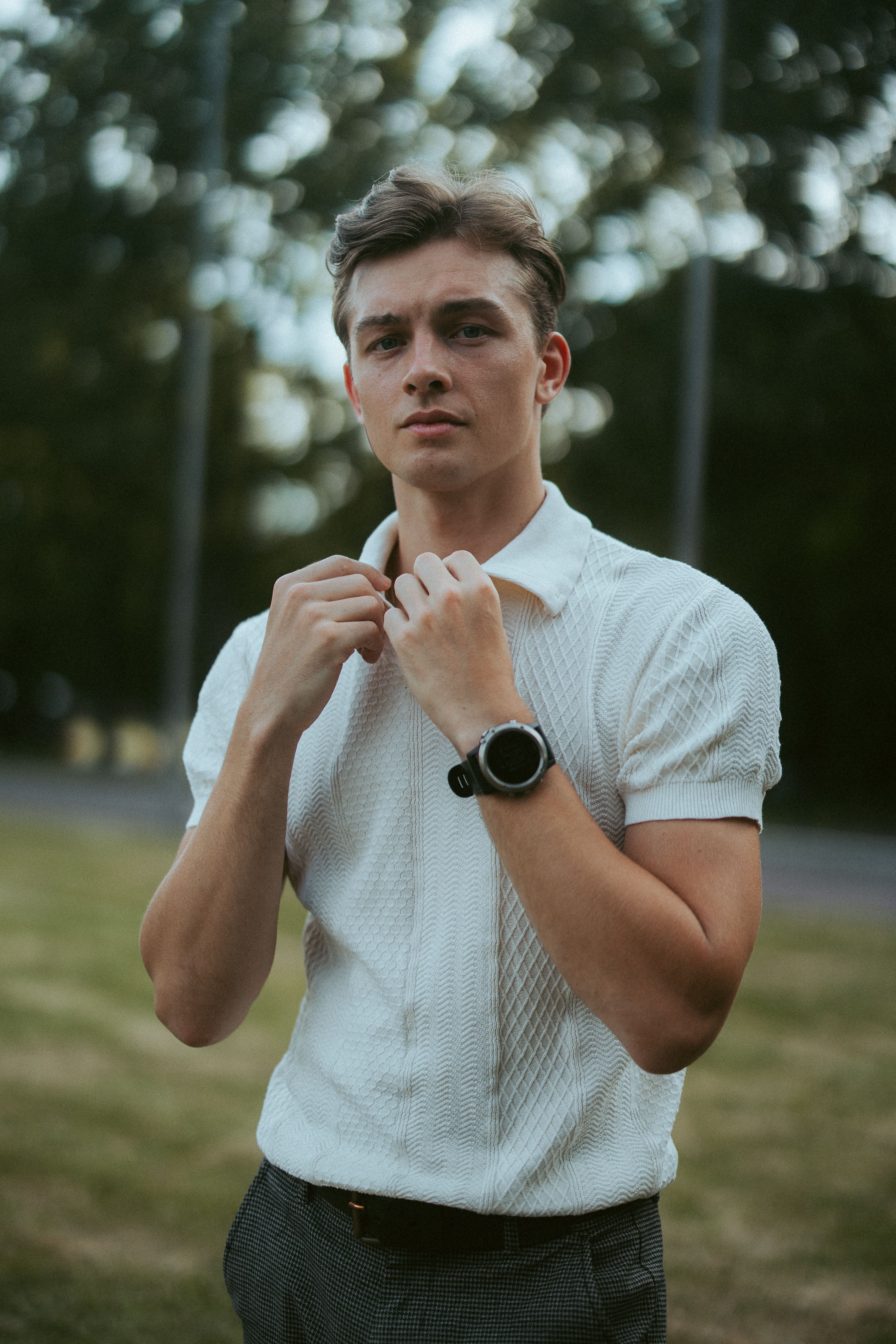 Portrait of a fashionable young man in a Berlin park, summer attire.