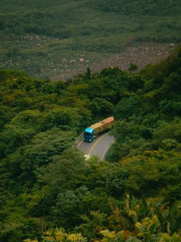 Aerial view of a truck navigating a winding mountain road through lush greenery in Tianguá, Brazil.