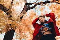 一位时尚的女士在秋色斑斓的树下摆出姿势，画面充满活力，颇具编辑时尚感