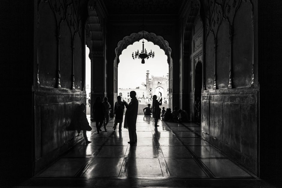 Black and white silhouettes inside an ornate mosque in Lahore, capturing historic architecture and cultural ambiance.
