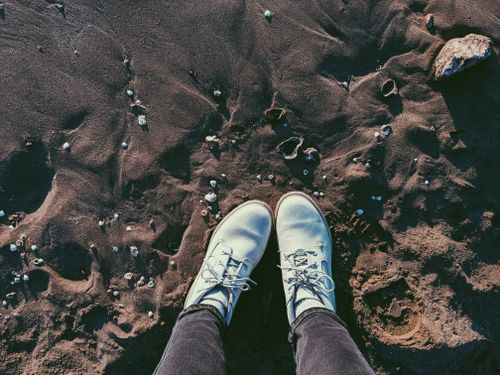 Free Perspective view of white boots standing on sandy beach with seashells at Shorncliffe, QLD. Stock Photo