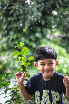 Young boy enjoying a rainy day in lush greenery, capturing childhood joy and innocence in Nilambur, India.