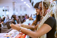 两位发型独特的时尚女士在室内柜台边，于热闹的环境中微笑