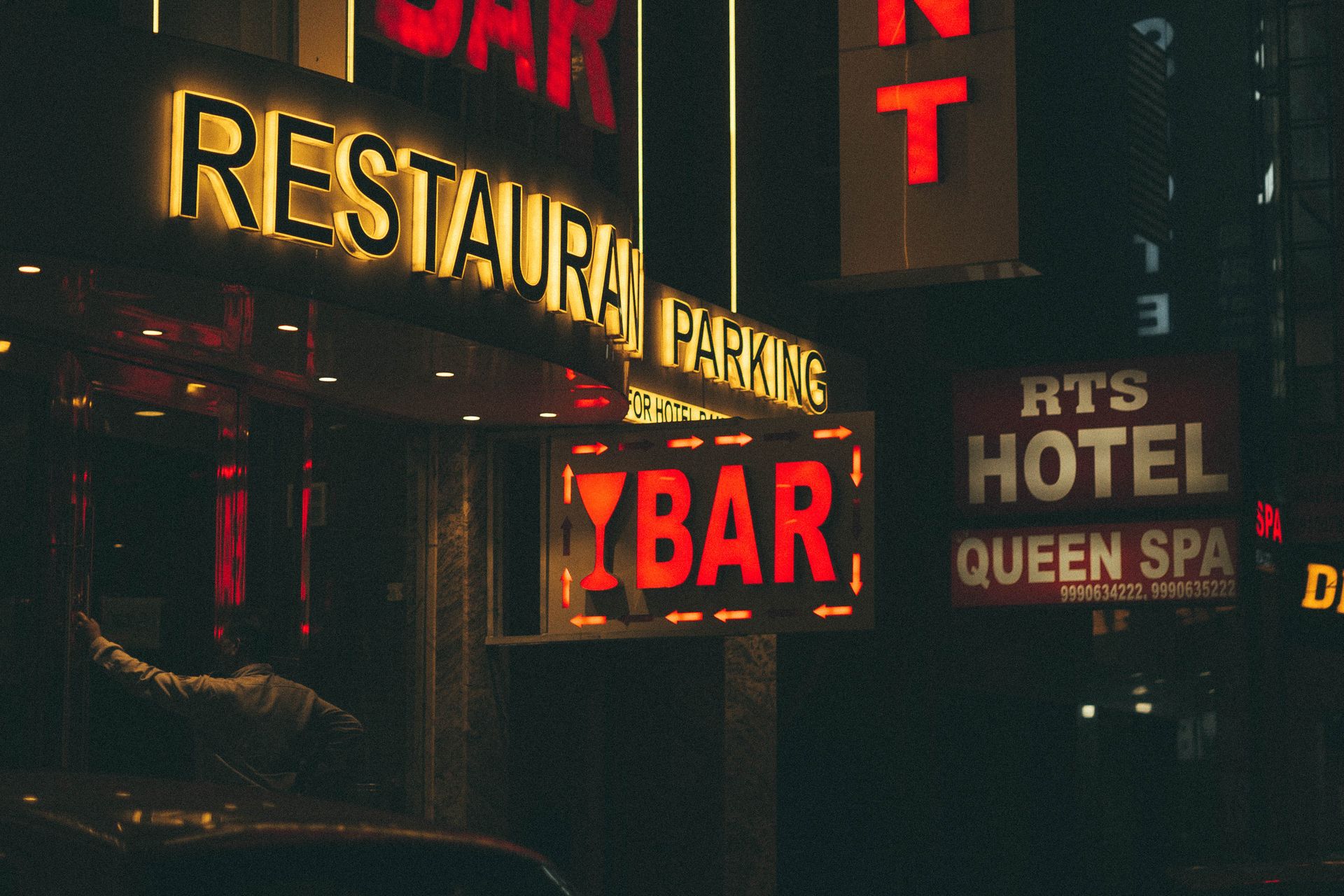 Vivid neon signs for bar and hotel on a bustling street at night, adding vibrant energy to the urban scene.
