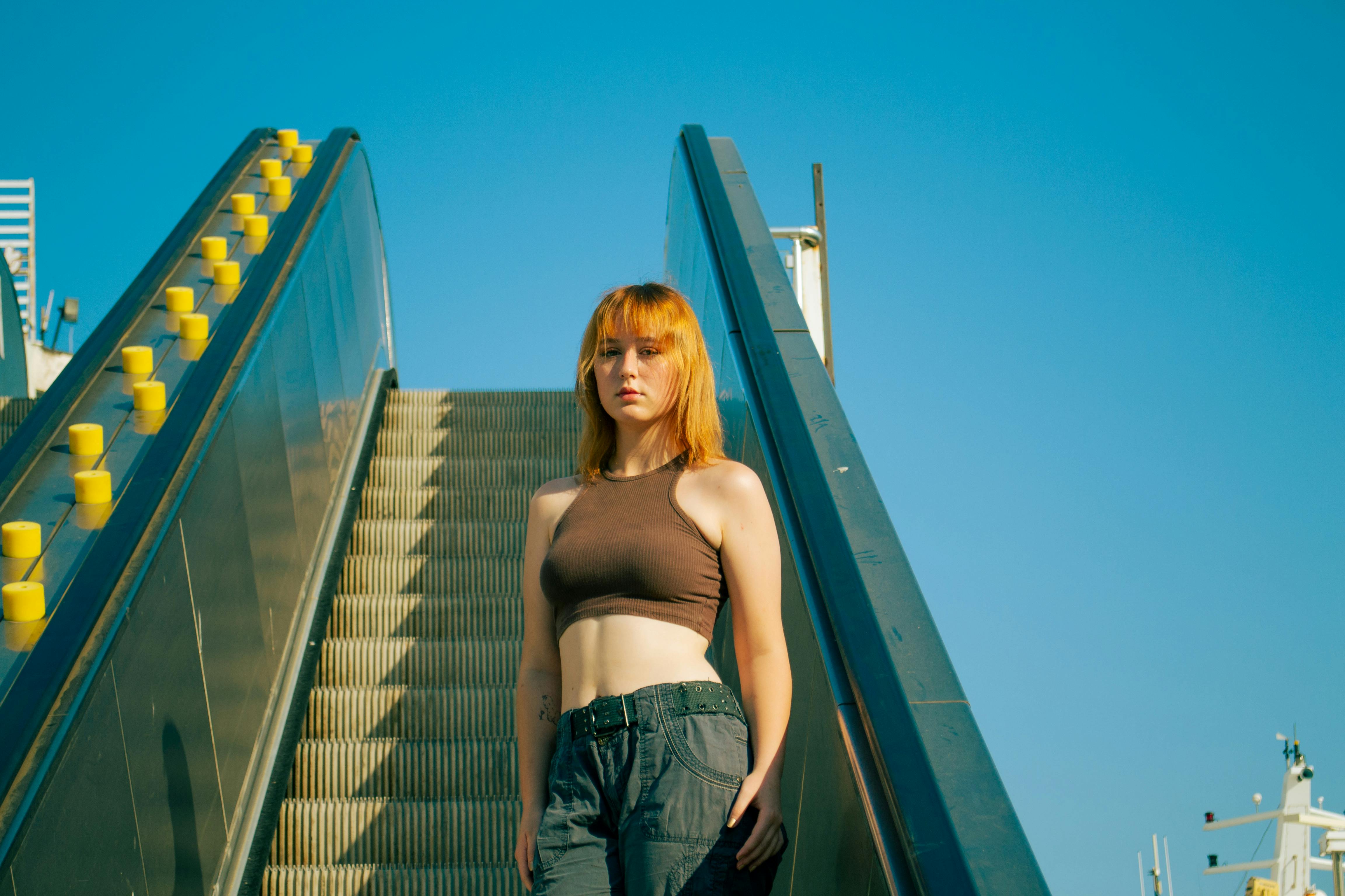 a woman standing on an escalator with her hair in a ponytail