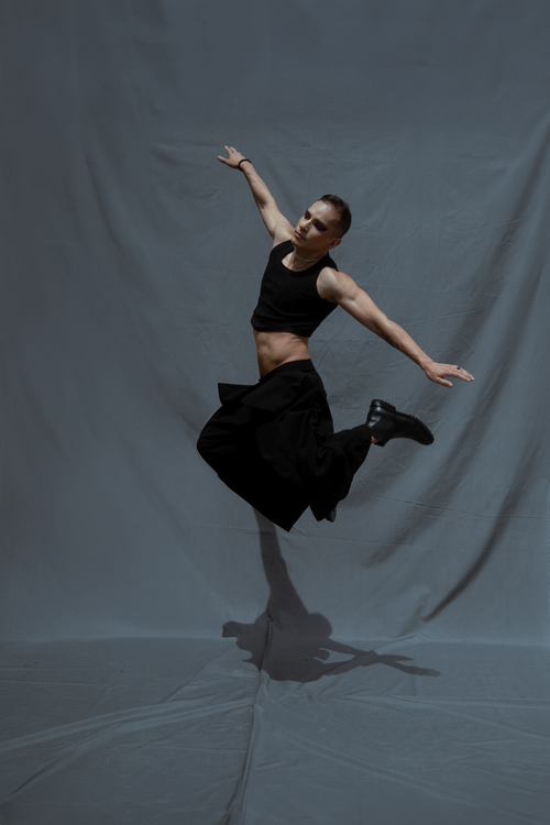 Free Male dancer showcasing energy and grace in a powerful leap indoors. Stock Photo