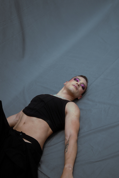 Free A stylish individual with dramatic makeup, lying on a studio floor. Captivating urban fashion photography. Stock Photo