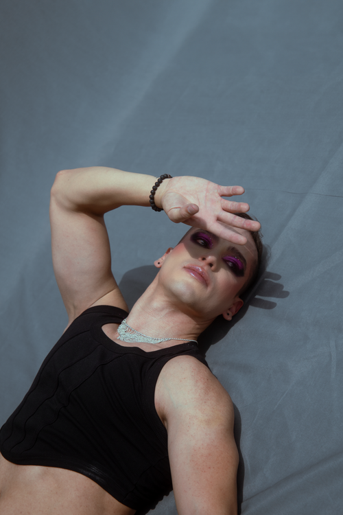 Free Stylish male model with bold makeup and black attire posing in a dramatic fashion style. Stock Photo