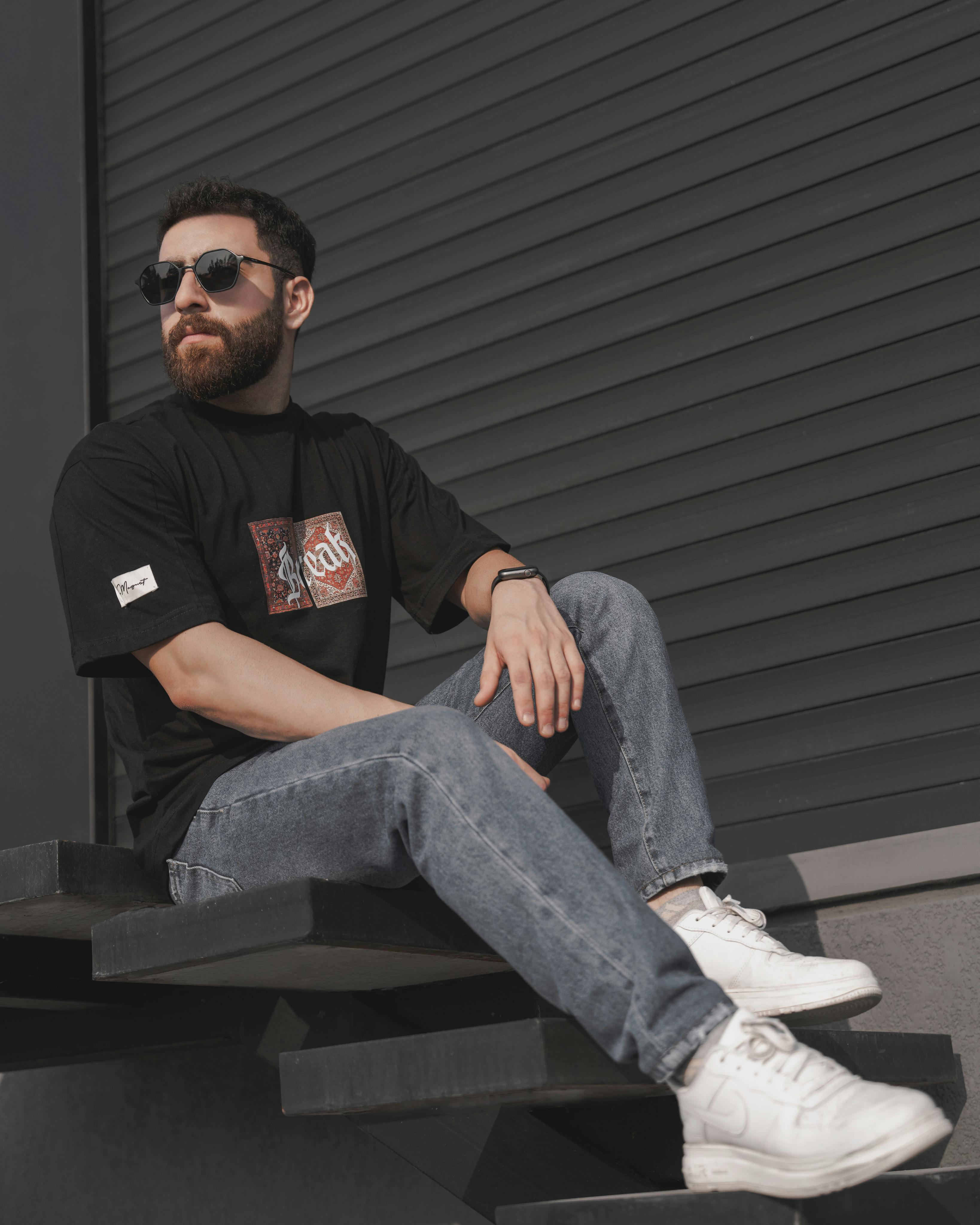 a man with beard and sunglasses sitting on steps