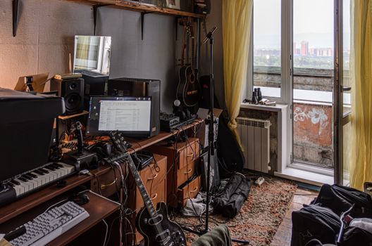 A cluttered home studio filled with musical instruments and sound equipment.