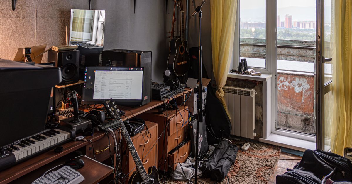 Home studio desk with audio interface, studio monitors, microphone, headphones and a computer running a DAW