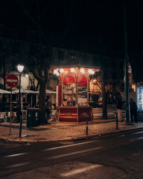 Free A cozy street kiosk illuminated at night in Lisbon, offering a glimpse of urban life in Portugal. Stock Photo