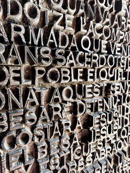 Close-up of a textured wall with sculpted text in Barcelona, Spain.