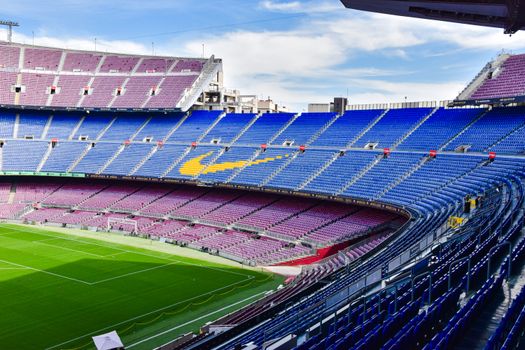 A wide-angle view of the iconic empty stands at Camp Nou, Barcelona's renowned football stadium under a clear sky.