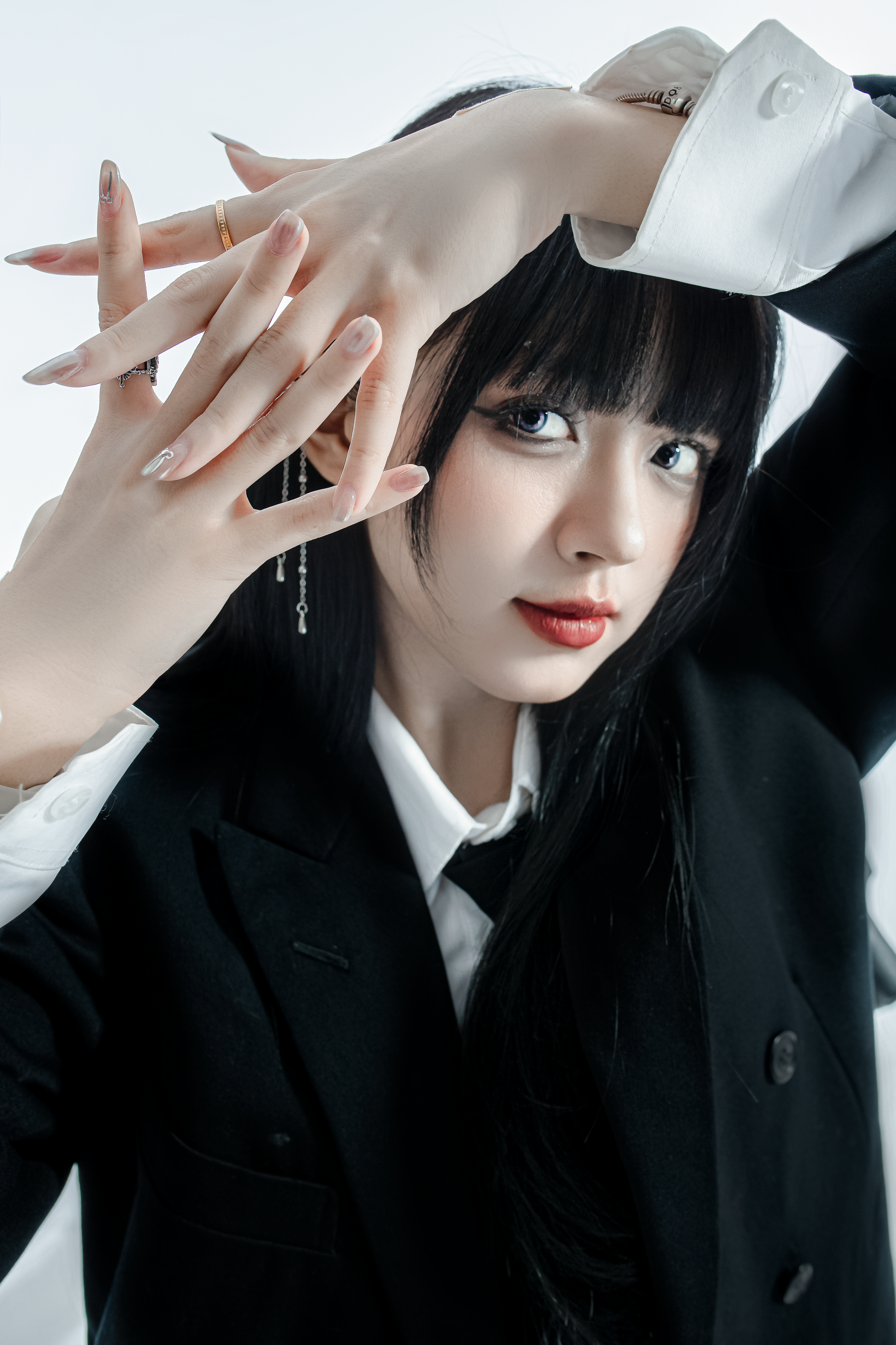 Elegant young Asian woman posing creatively in a studio, showcasing modern fashion.