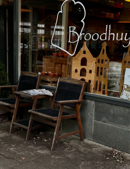 Charming outdoor seating area of a European café with rustic wooden chairs.